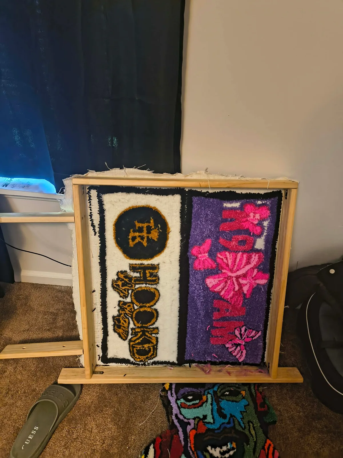 Two finished tufted panels side by side on the frame, one cream and gold, one purple with pink butterflies.
